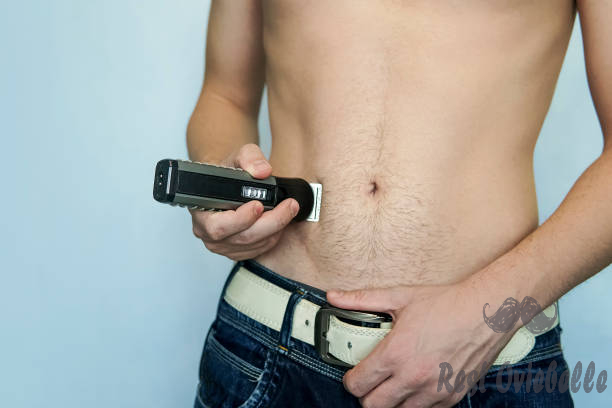 closeup of a young man trimming the hair of his pubis with an electric trimmer. concept of a clean healthy body for men.